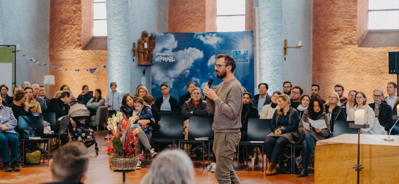 Mann spricht vor Publikum in einem Saal.