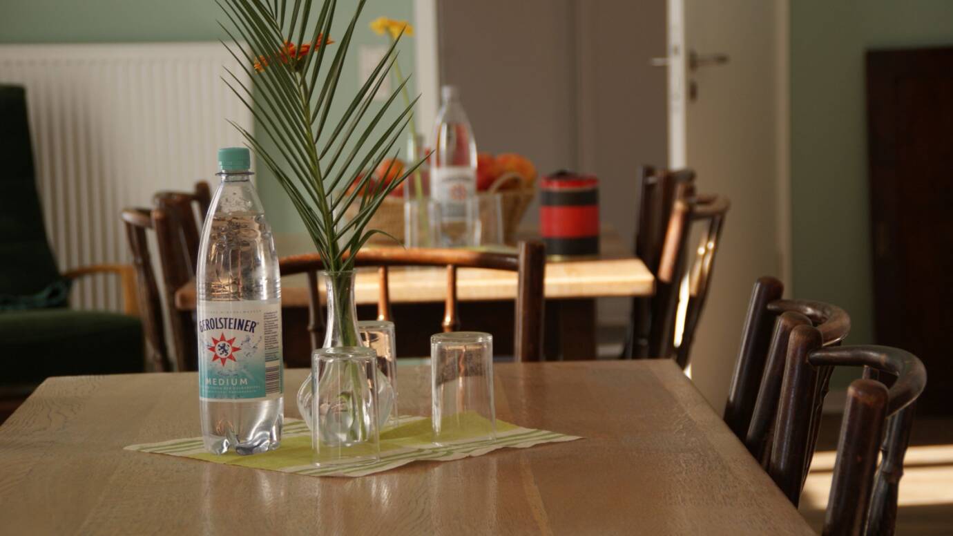 Holztisch mit Wasserflasche und Glasvase im Café