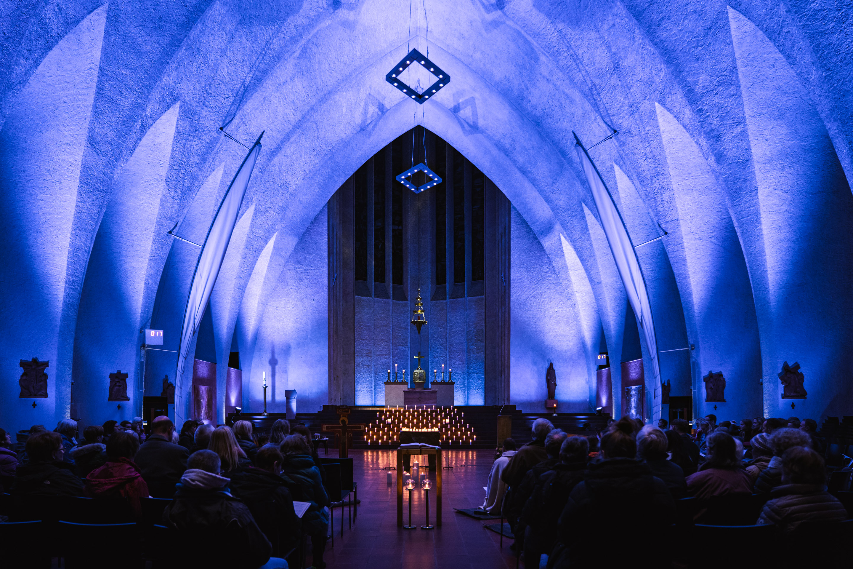 Blau beleuchteter Kirchenraum mit Altar und Kerzen