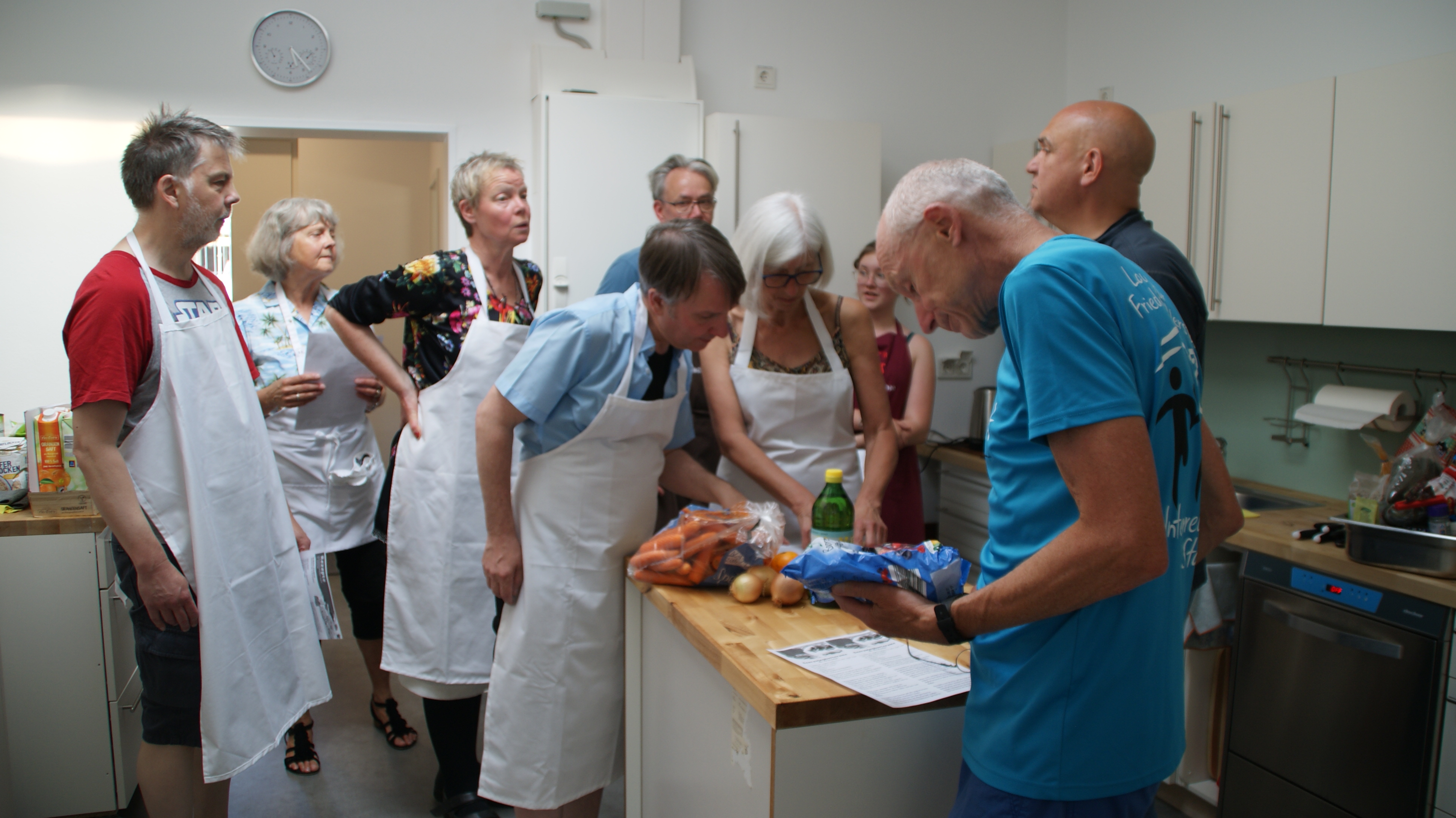 Gruppe beim Kochkurs in Küche mit Schürzen