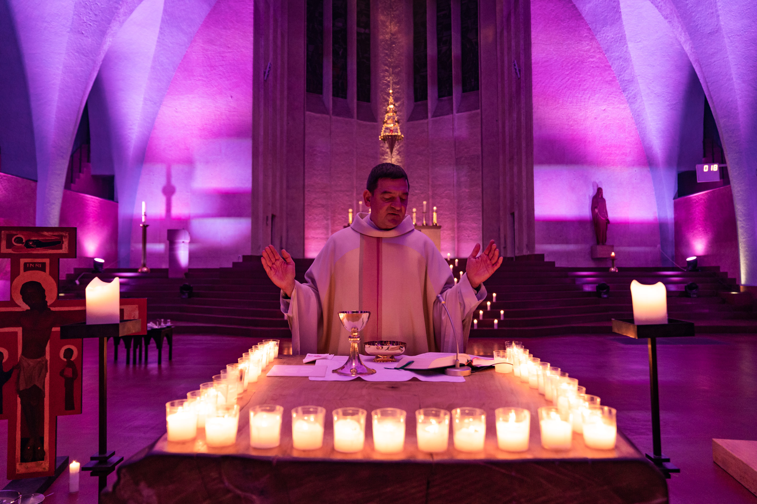 Priester zelebriert Messe bei Kerzenschein in Kirche