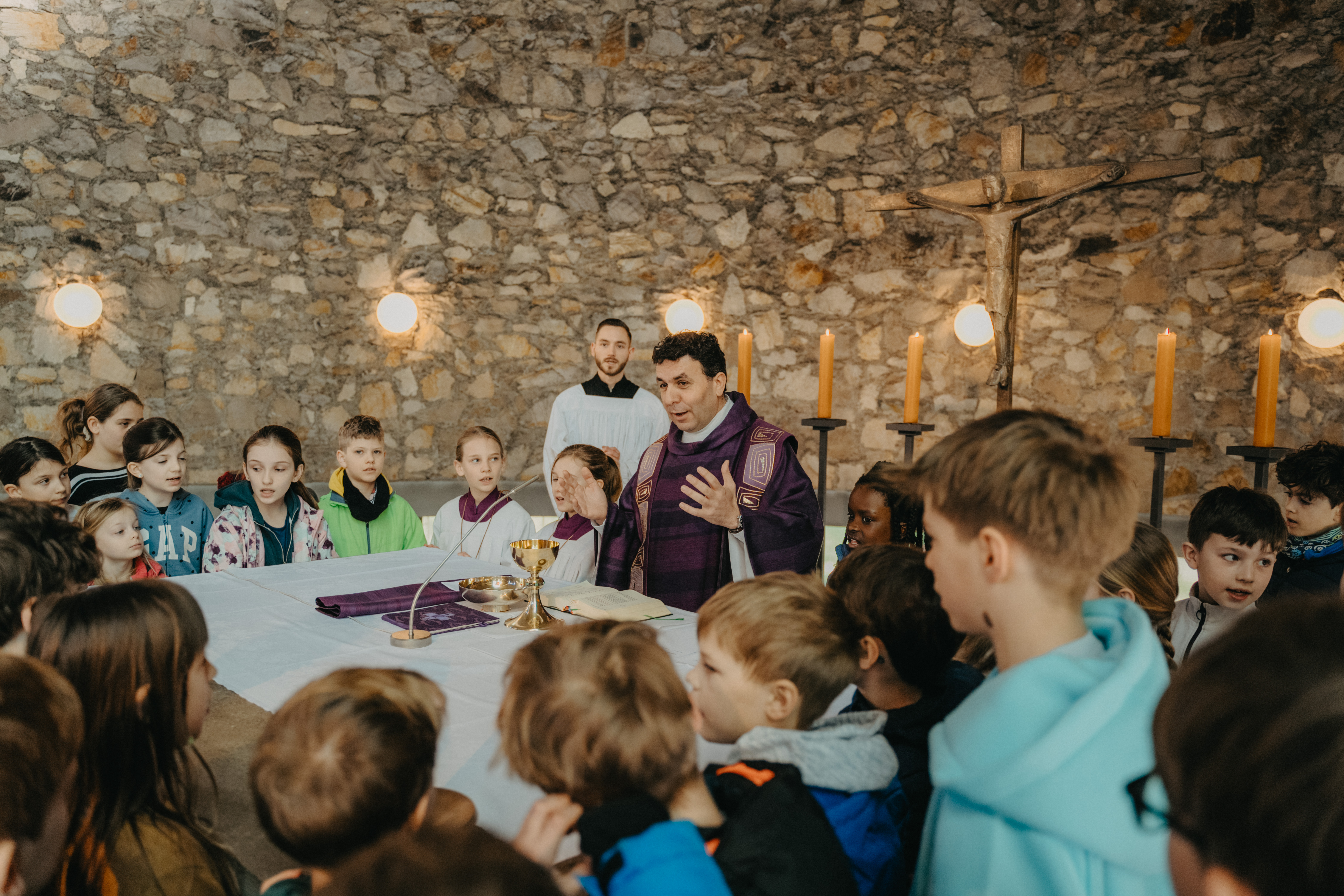 Priester erklärt Kindern Messe am Altar